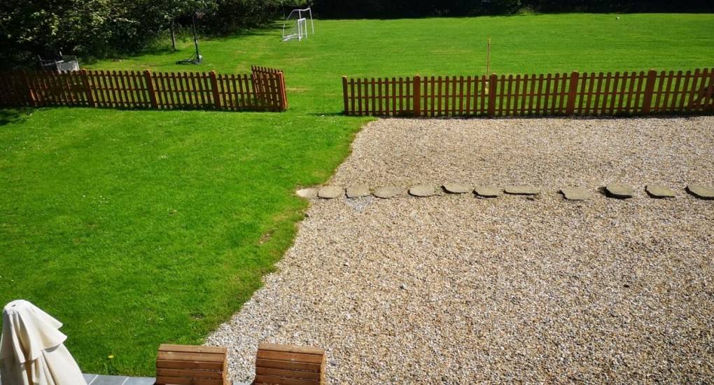 garden area with grass, stones and fence