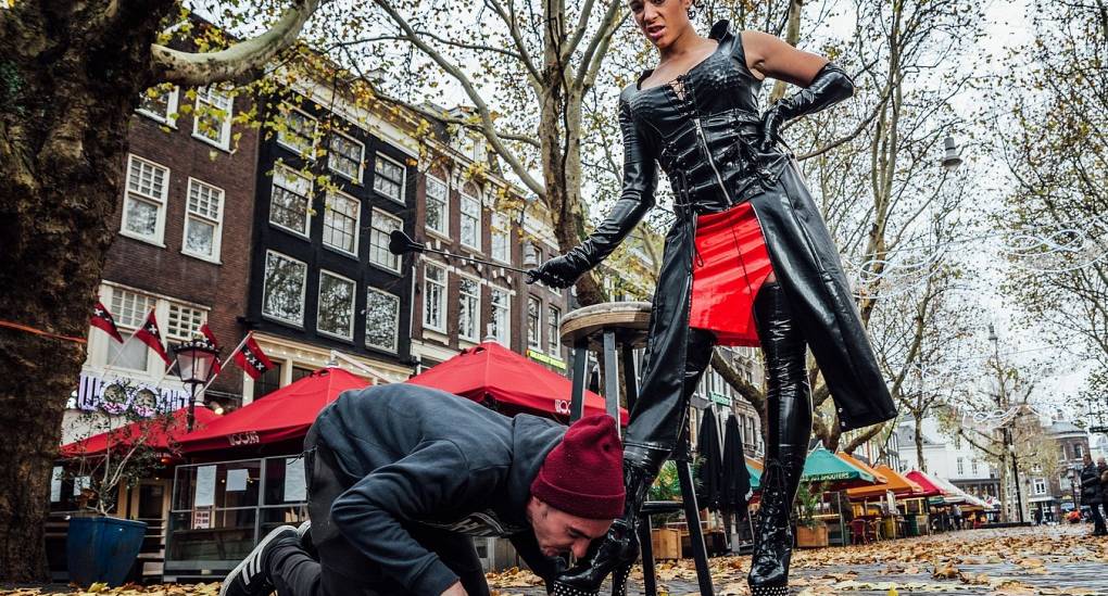 Stitched up stag kissing a Dominatrix's boot on a special bar tour