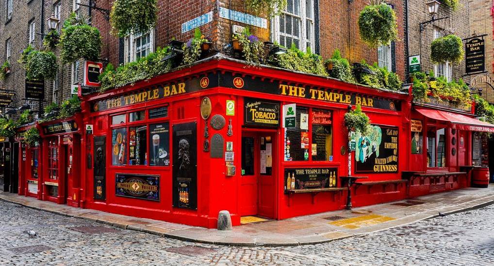 The Temple Bar pub with iconic red facade and hanging baskets on cobblestone corner, landmark for a Dublin stag do.