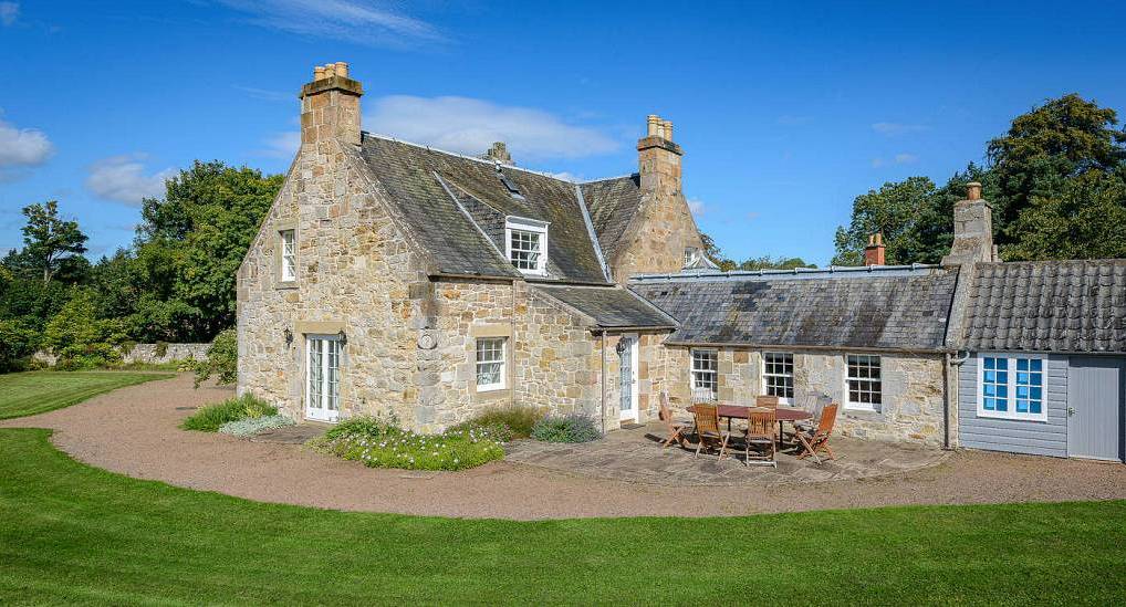 Traditional stone cottage exterior with stone patio and garden furniture at Foxglove Cottage near Edinburgh.