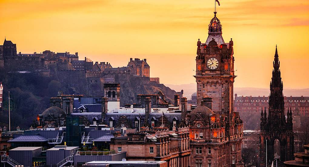 Sunset skyline over Edinburgh featuring Balmoral clock tower and Scott Monument, vibrant setting for an Edinburgh stag do.