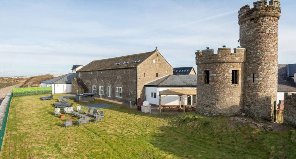 View from the back of the property with grounds, garden furniture and watch tower in the background
