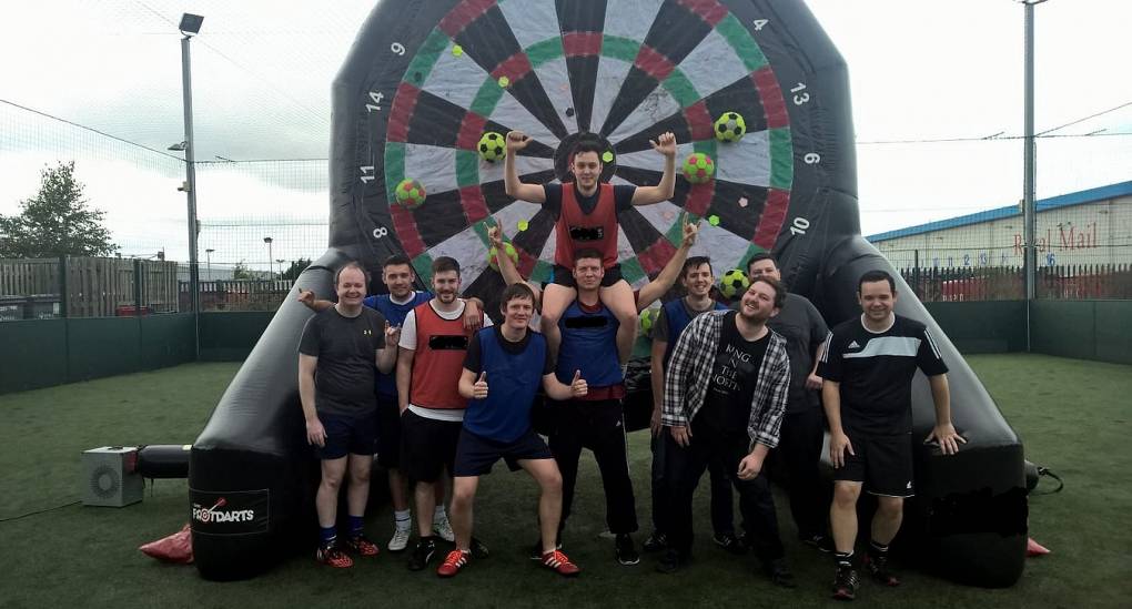 Stag do pose in front of footdart board