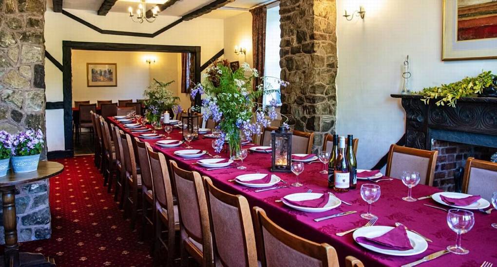 Banquet dining table set with magenta tablecloth, wine glasses and stone pillars at Ross Lodge in Forest of Dean.