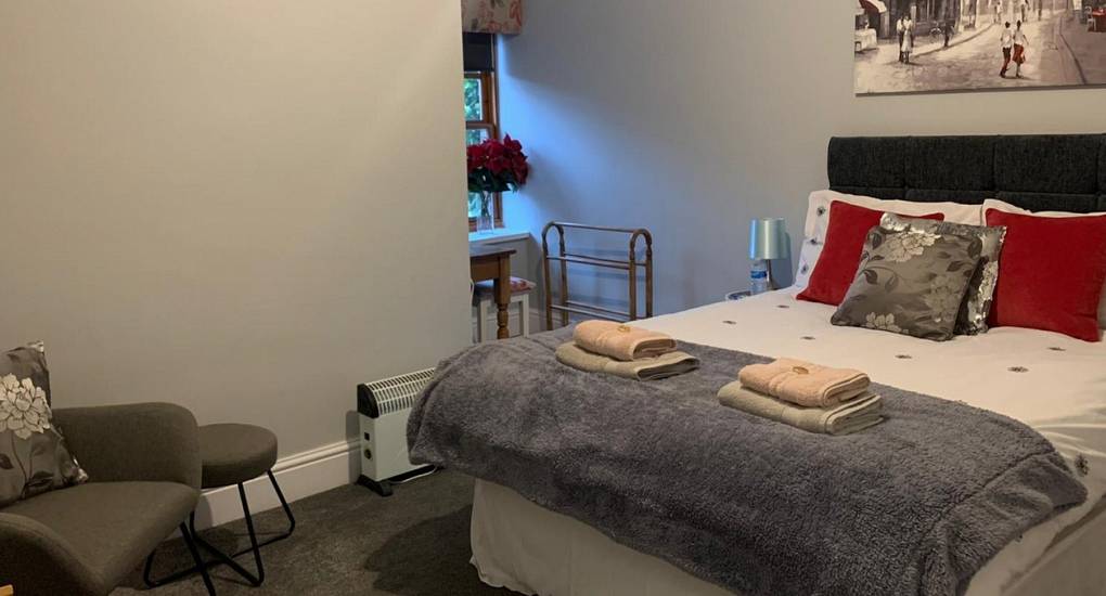 Bedroom with newly made double bed with folded towels placed on the bed runner