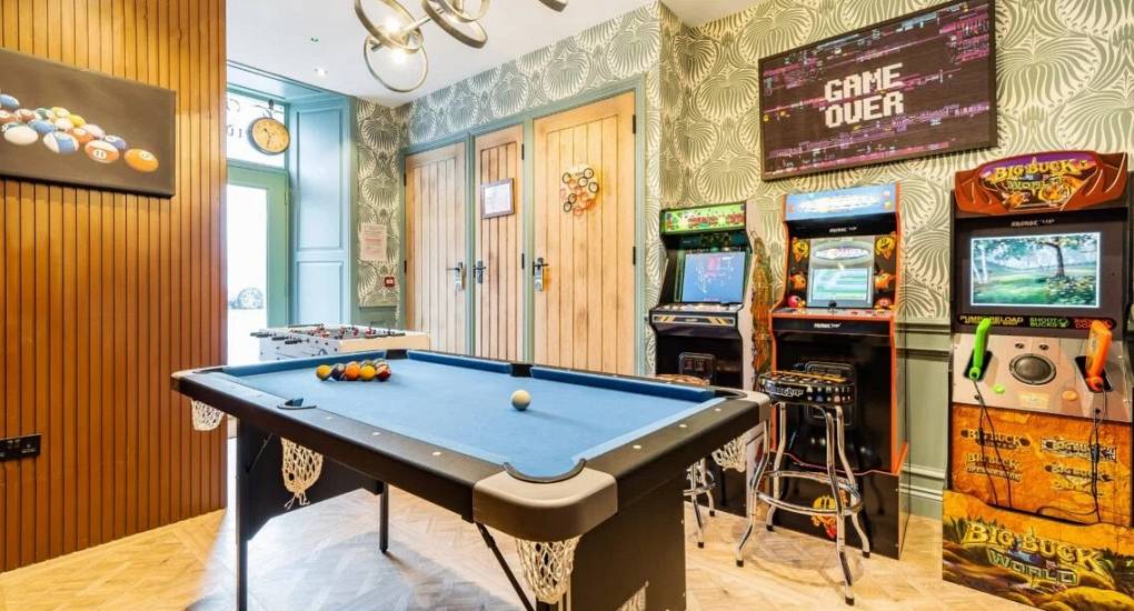 Games area with small pool table and three arcade machines along the wall