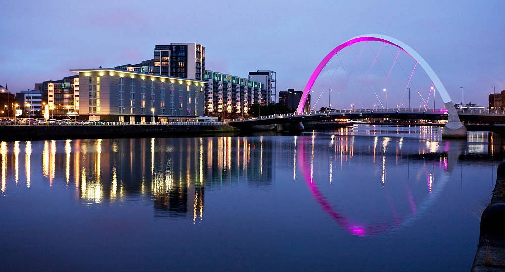 Illuminated Clyde Arc bridge reflecting vibrant lights over the River Clyde at night, iconic setting for a Glasgow stag do.