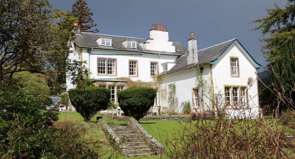 Grand white country estate exterior with stone garden steps and lawn at The King, party house near Glasgow.