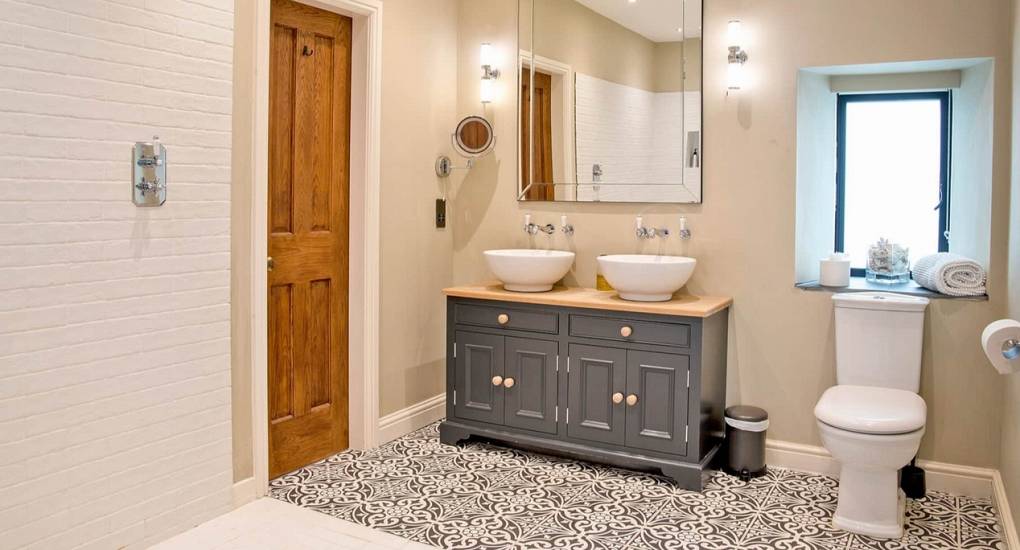 Luxury bathroom with double sinks and walk-in shower at Godfrey Manor Peak District hen house.