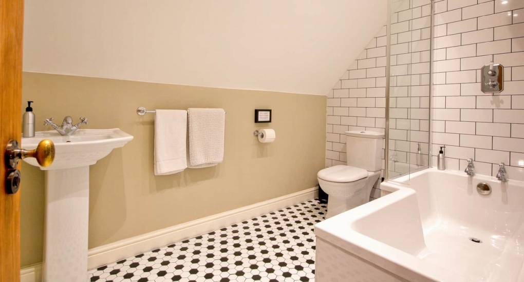 Modern tiled bathroom with full bathtub at Godfrey Manor, a premium Derbyshire hen party stay in the Peak District.