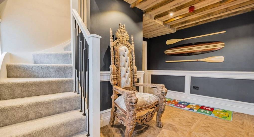 Hallway area with decorative oars on the wall and a grandiose throne style seat  