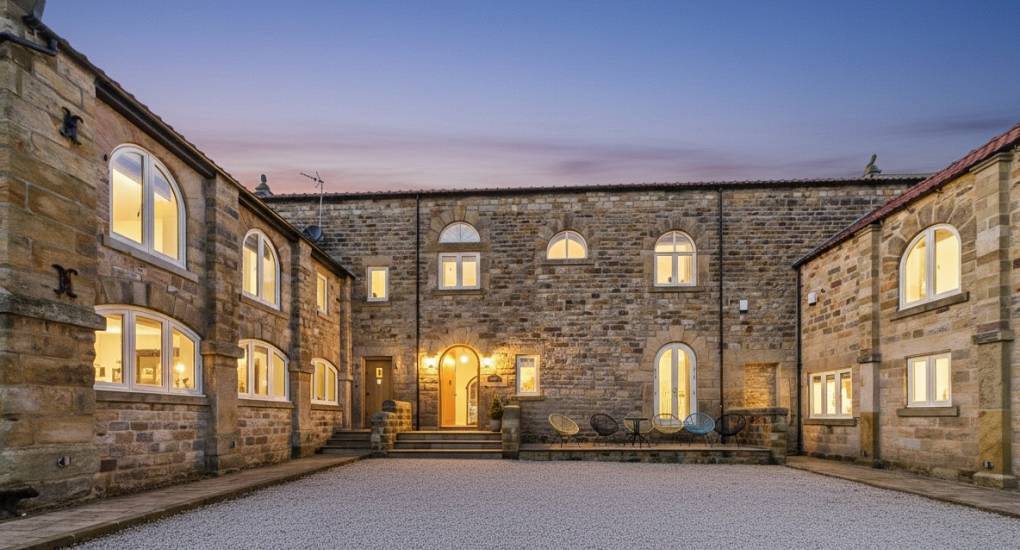 Illuminated stone courtyard exterior at dusk at Hookstone Estate, large hen party venue near Harrogate.