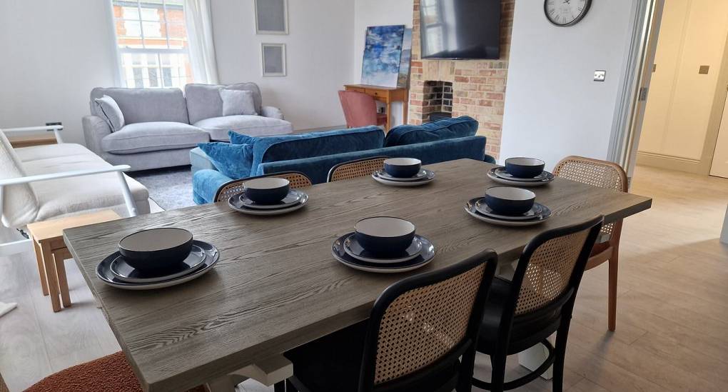 Dining table view of open plan living with open brick feature wall