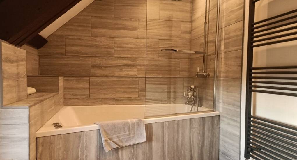 fully tiled bathroom with bath and shower