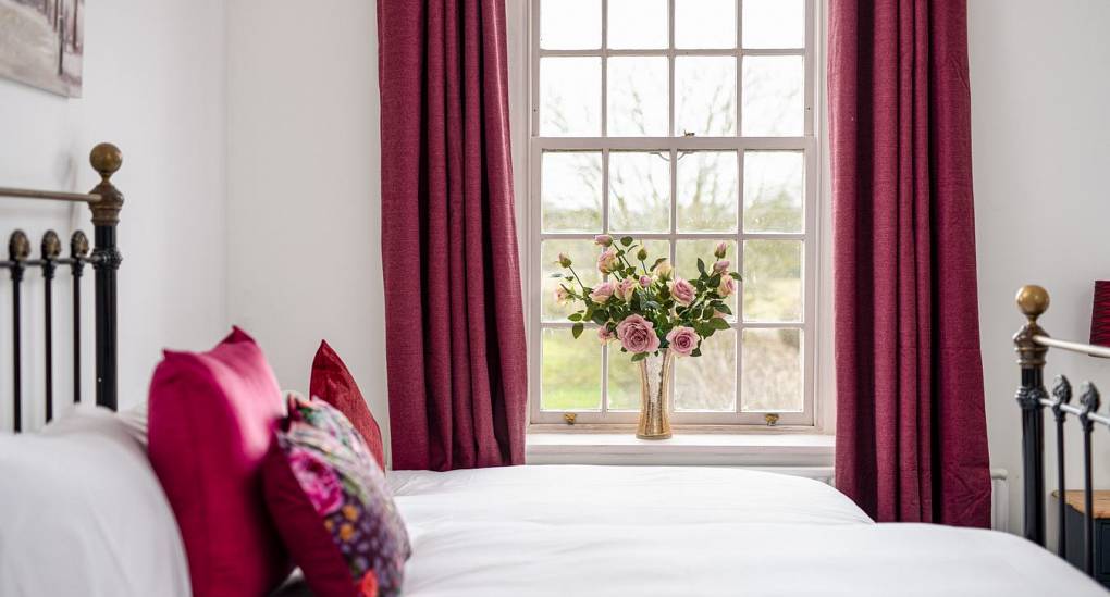 Double bed with flowers displayed in the window