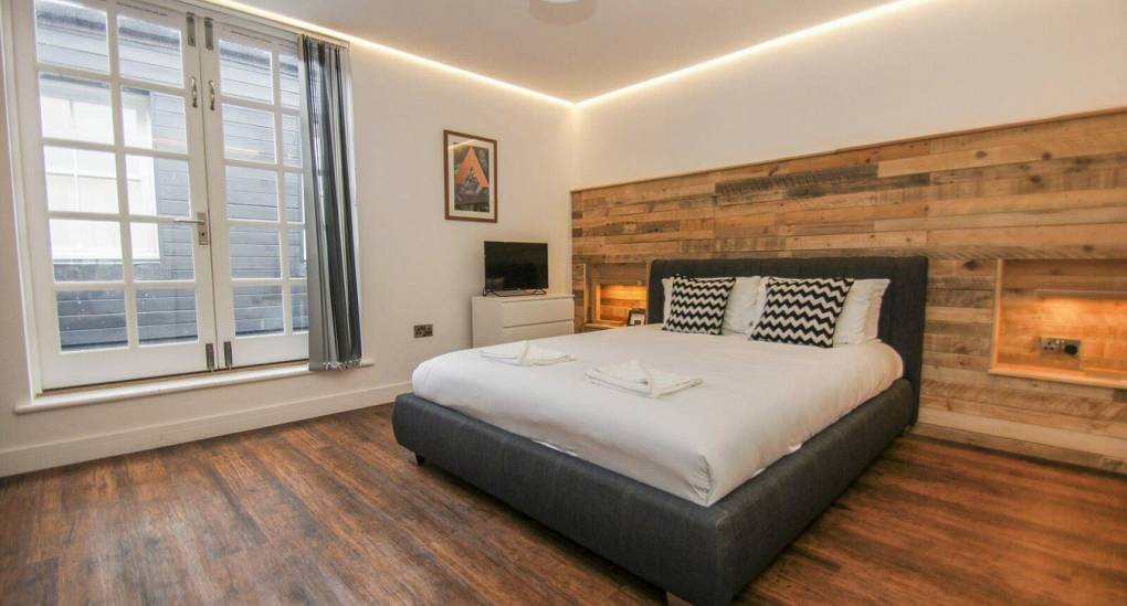 Large bedroom with wooden floor and windows