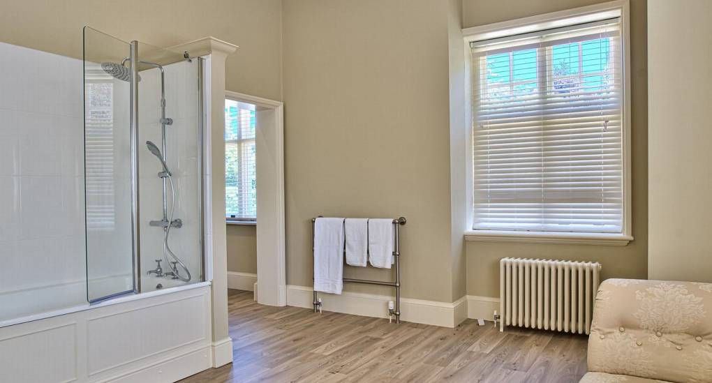 Large bathroom with sofa and shower over bath