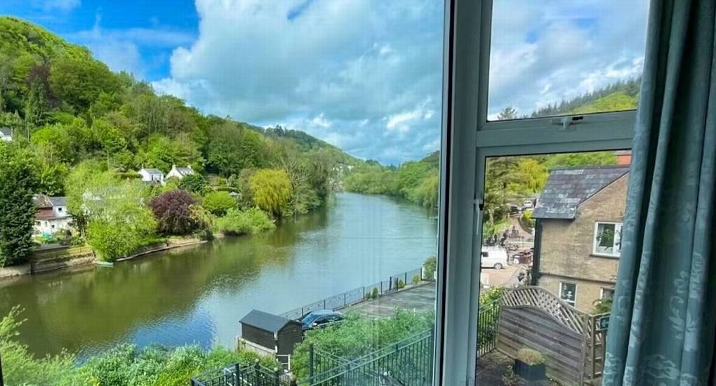 Window view looking out over scenic winding river and lush green hills from White Horse House, Herefordshire.