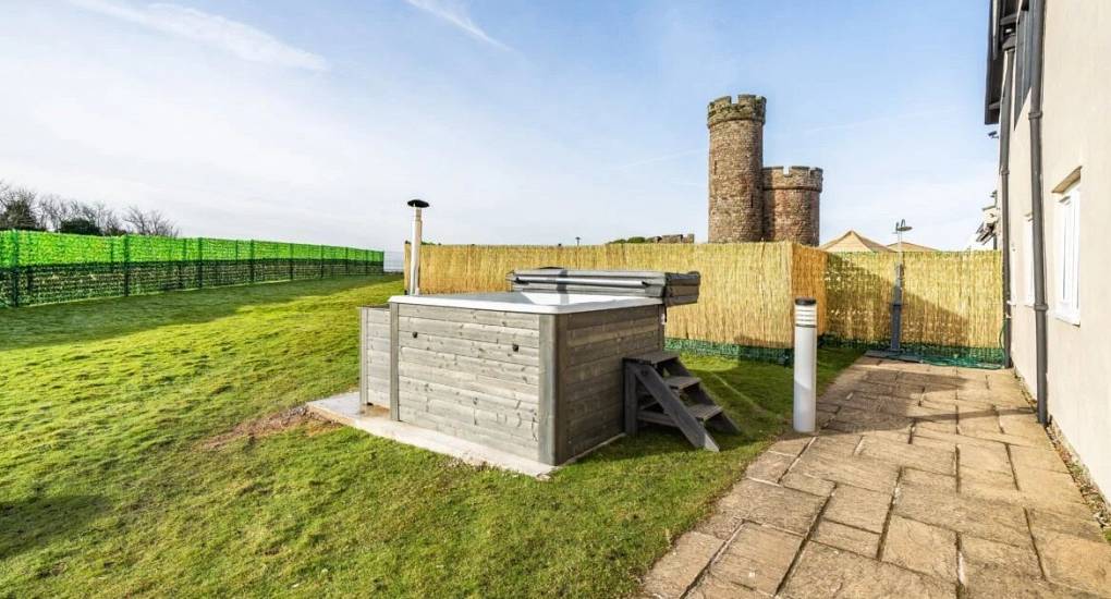 Hot tub in the gardens with fenced privacy screen with a watch tower in the background