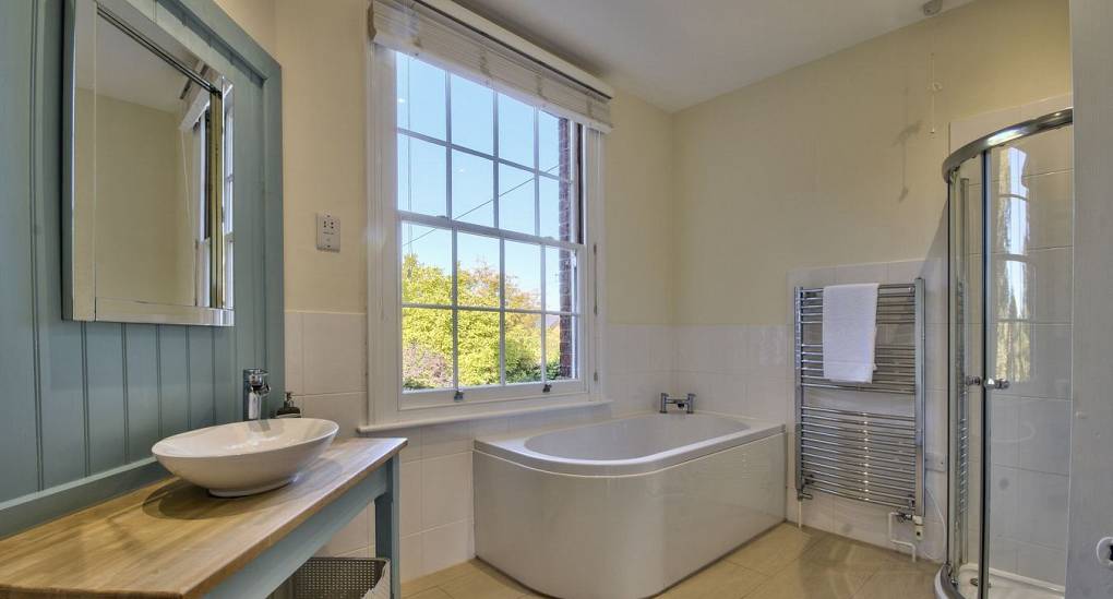 Large bathroom with bath under window and walk in shower