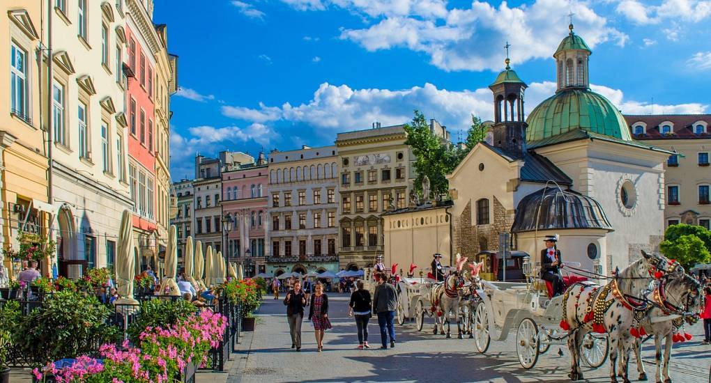 Horse-drawn carriages by St. Adalbert's Church on Kraków Main Square, charming setting for a Krakow hen do.
