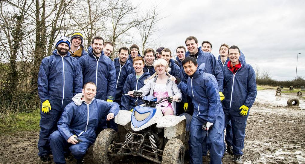 Lads on a stag weekend posing with quad bike in mud