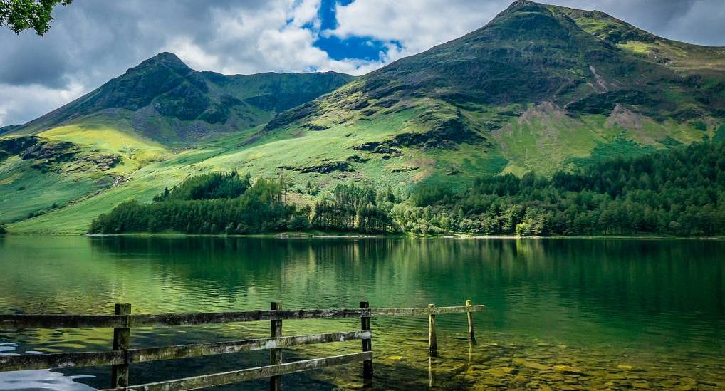 Tranquil lake reflections and green mountain fells in the Lake District, scenic backdrop for a Lake District hen do.