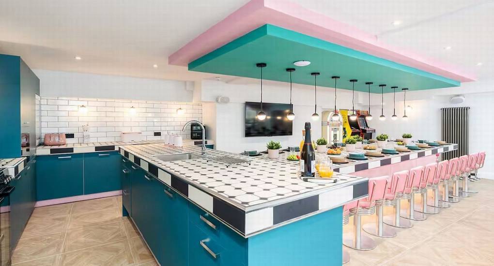 Vibrant retro kitchen and breakfast bar with pink bar stools at Hiltop Panorama party house in Lake District.
