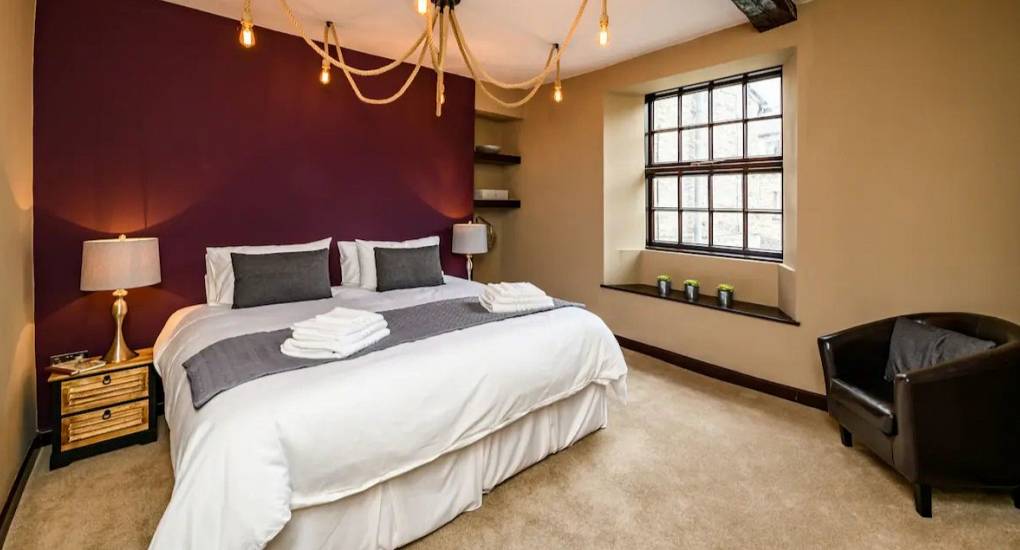 Large bedroom area with made up double bed and typical bedroom furniture 
