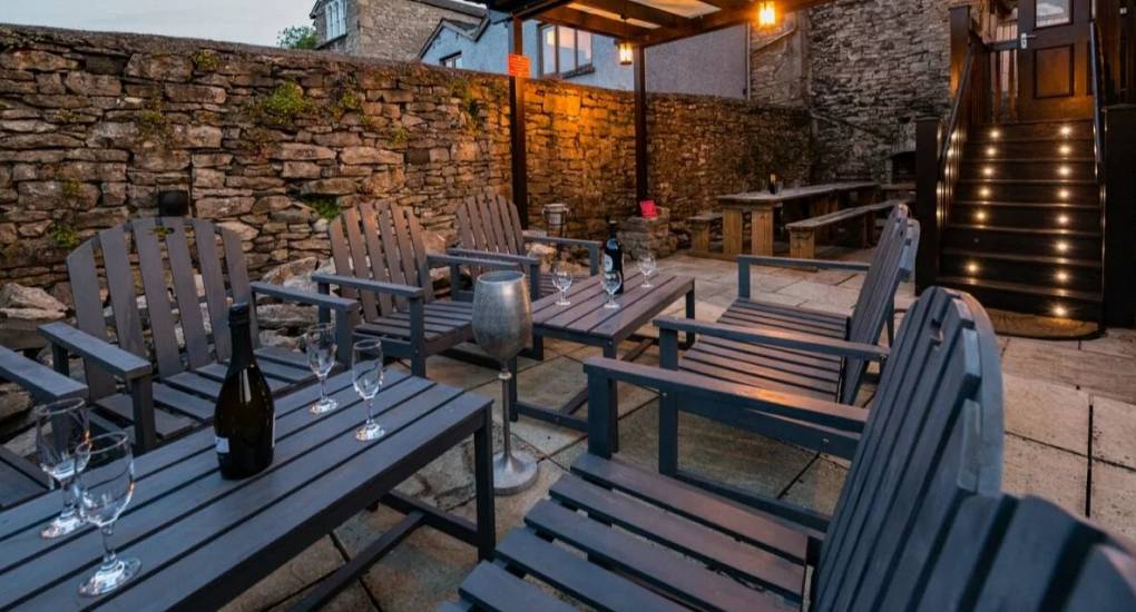 View of the stone decking area with pub style seating and hot tub in the background 