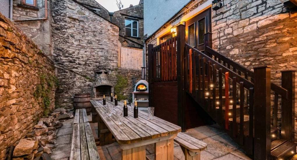 Rustic stone courtyard with long picnic table, wood fired oven and fairy lights at Rydal Pub, Lake District.