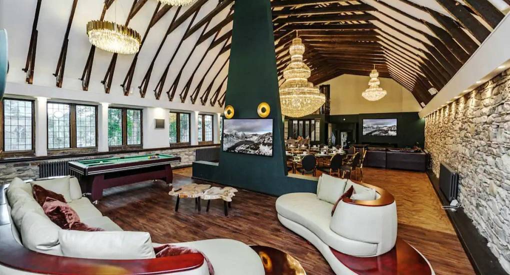 Grand vaulted living room with chandeliers, curved sofas and pool table at The Grand Hall in Lake District.