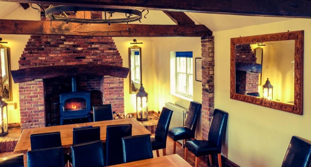 Dining area with feature exposed brick open fire and seating for a large group