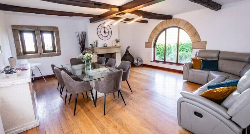 Spacious open plan living room with glass dining table and grey leather sofas at The Stabletree near Leeds.