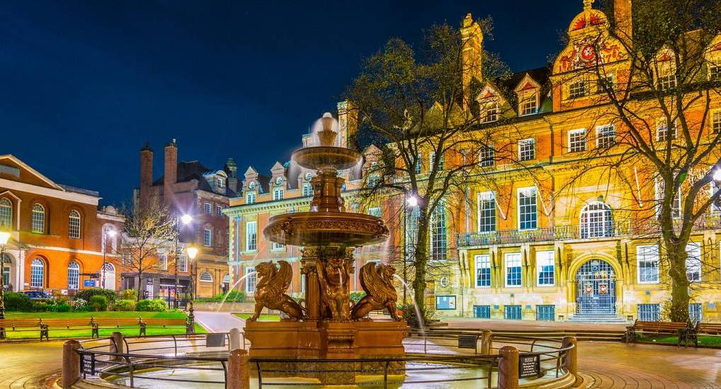 Illuminated fountain in Town Hall Square at night with Leicester Town Hall in the background for a Leicester stag do.