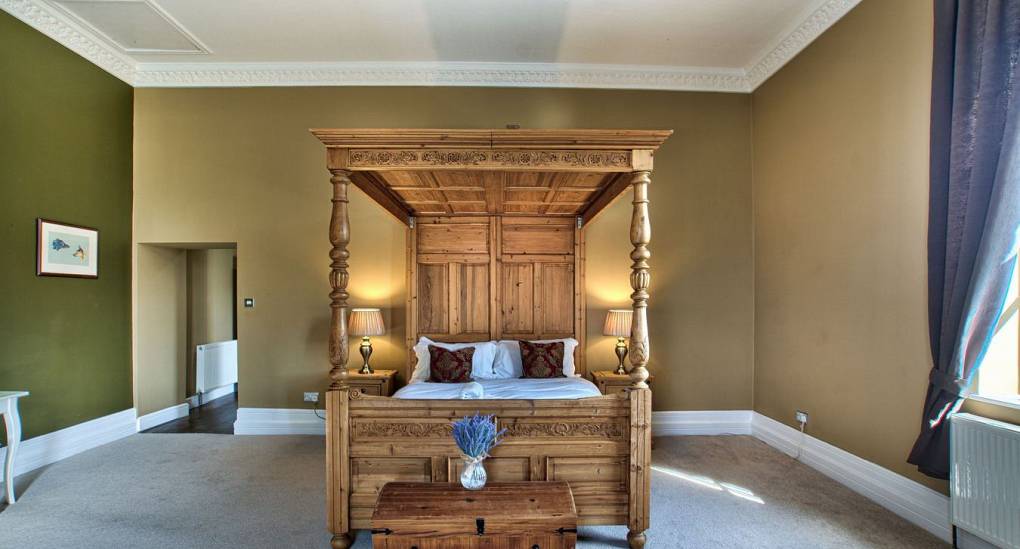 Wooden four poster bed in bedroom