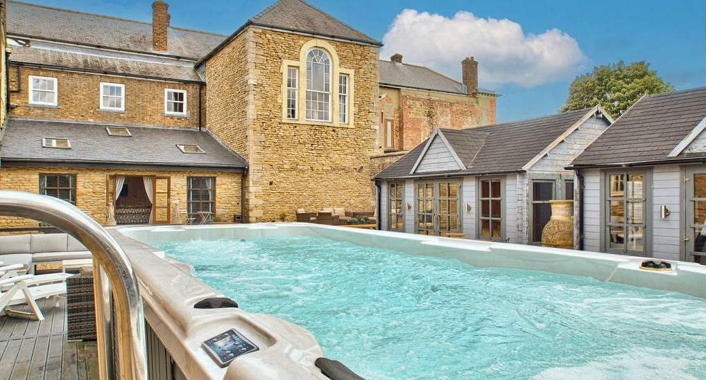 Large outdoor swim spa jacuzzi tub on stone terrace at Willow Creek Grade II listed hen party house near Lincoln.