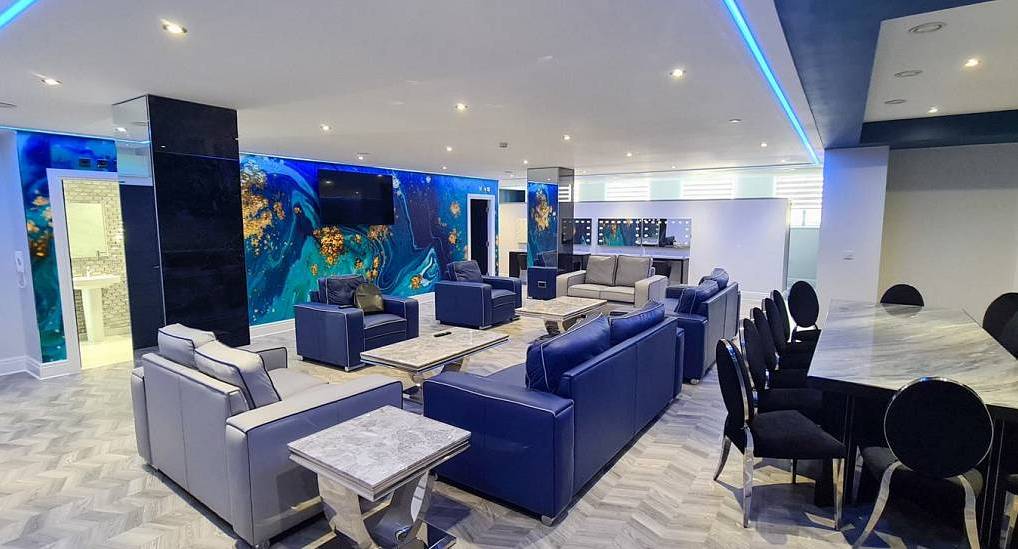Modern open plan lounge with blue leather sofas, marble dining table and blue feature wall at 14 Fourteens Liverpool.