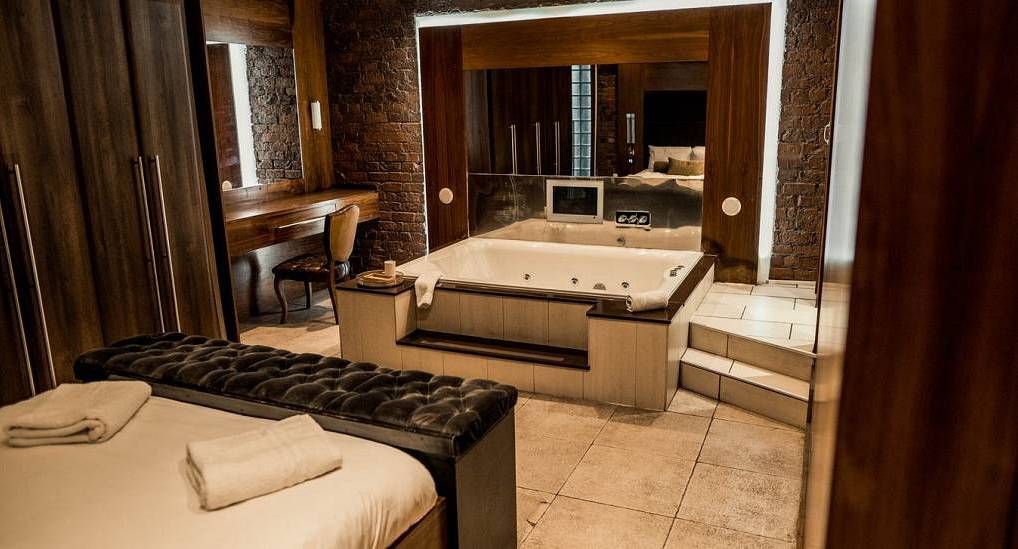 Luxury penthouse bedroom featuring a large sunken indoor spa jacuzzi tub and dressing table at The Party Pad Liverpool.