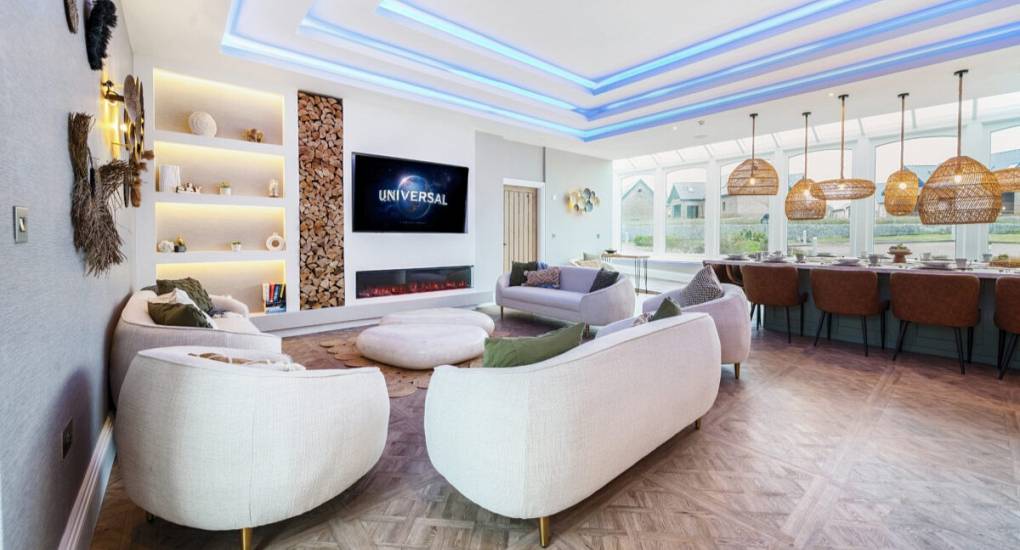 Lounge area featuring stylish curved white sofas and a large wall mounted tv