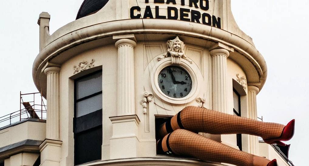 Teatro Calderón facade with playful burlesque legs sculpture beneath the clock tower, vibrant setting for a Madrid stag do.