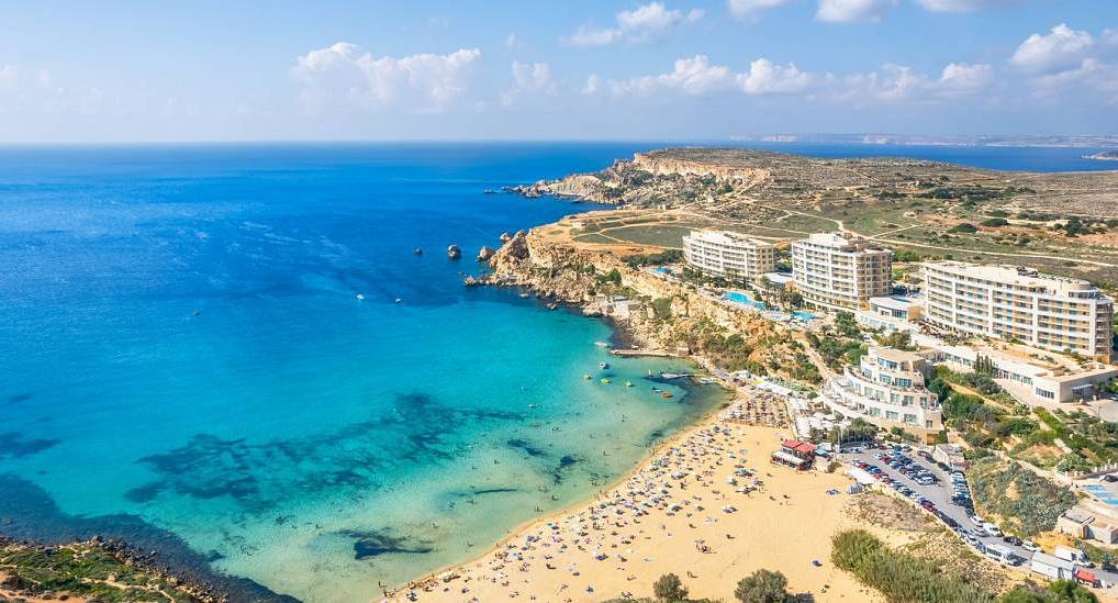 Golden Bay sandy beach and turquoise waters with cliffside resort, scenic coastal backdrop for a Malta hen do.