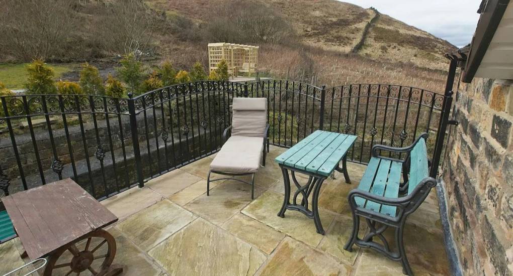 the balcony area with bbq and firepit with some garden chairs