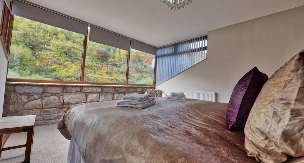 Bedroom three with a large feature window with foliage outside