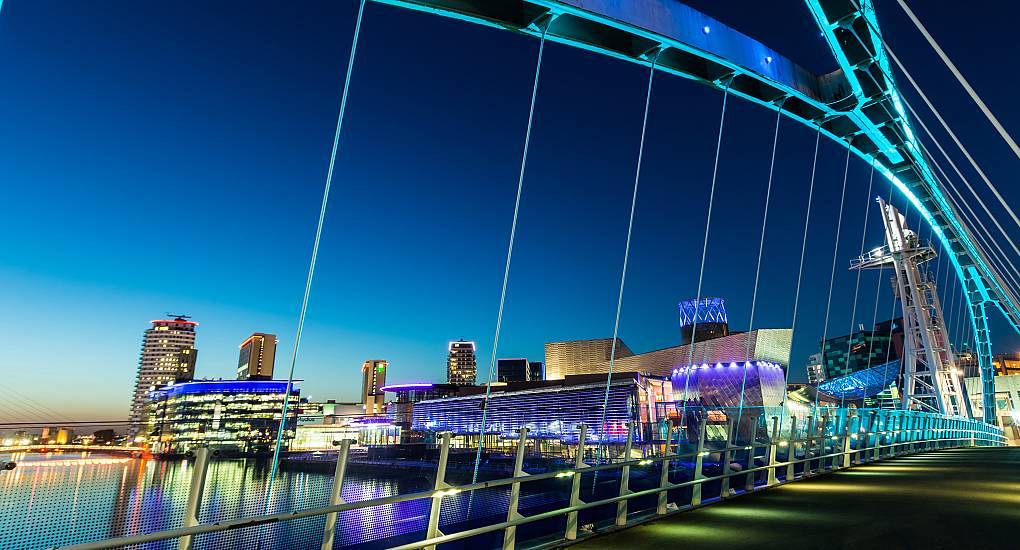 Illuminated MediaCityUK footbridge at Salford Quays at night, vibrant waterfront setting for a Manchester hen do.