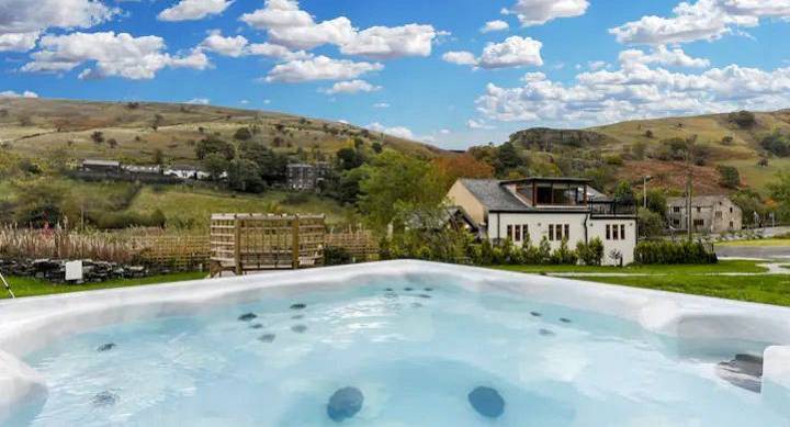 Outdoor bubbling hot tub looking out across green gardens and rolling countryside hills at The Canals near Manchester.