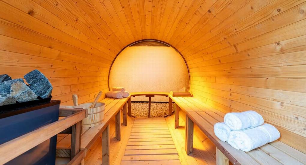 Interior of the large wooden barrel sauna for relaxation at the Lake District party house