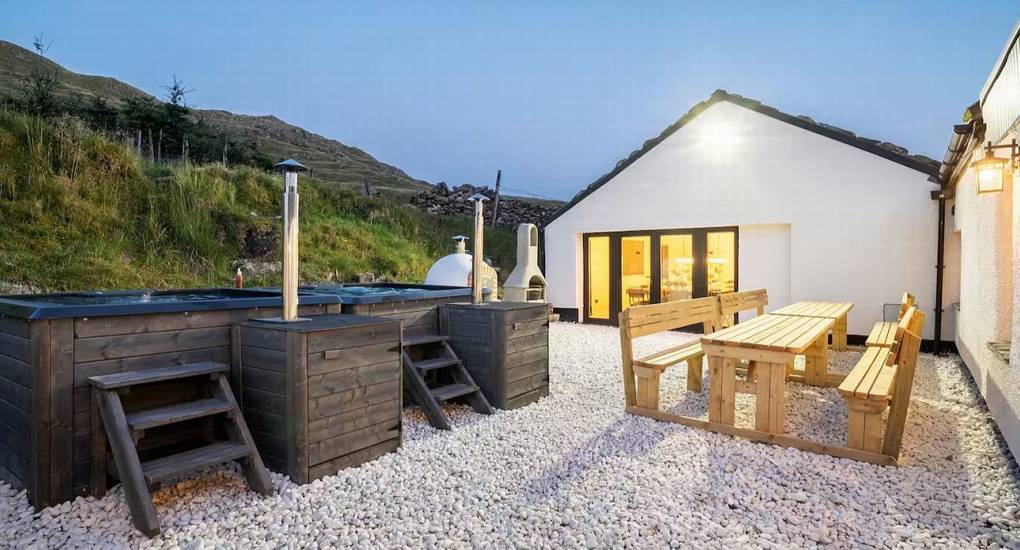 Manor on the Mountain luxury party house exterior at dusk with two illuminated hot tubs and outdoor seating