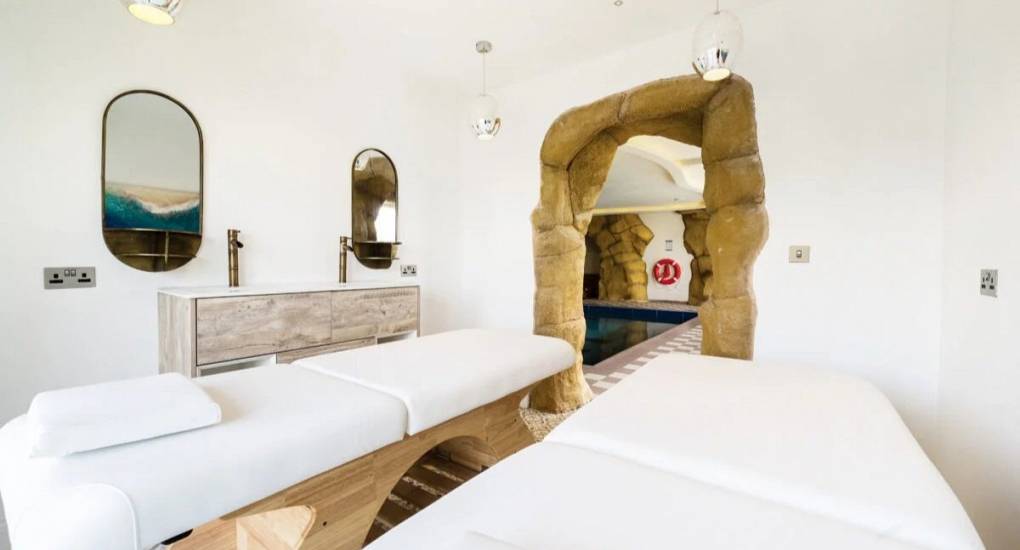 Massage room with two beds and doorway leading to the swimming pool