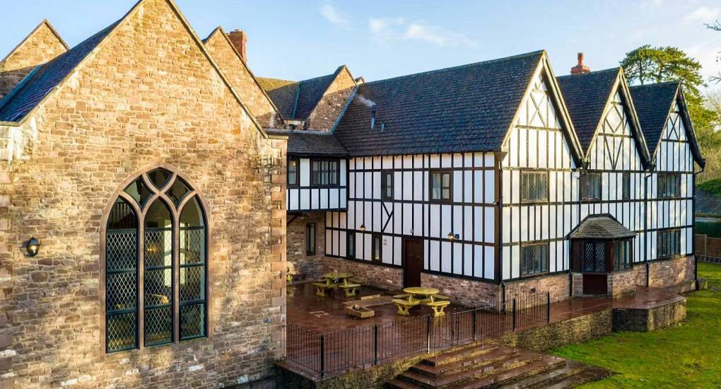 Historic Tudor style manor house exterior with stone section, Gothic window and patio terrace at Monmouth Manor.
